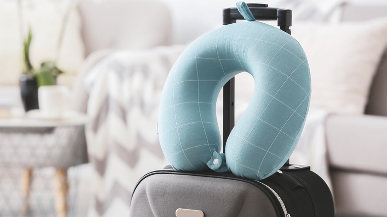 A blue neck pillow on top of a suitcase