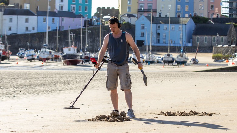 man beachcombing with metal detector