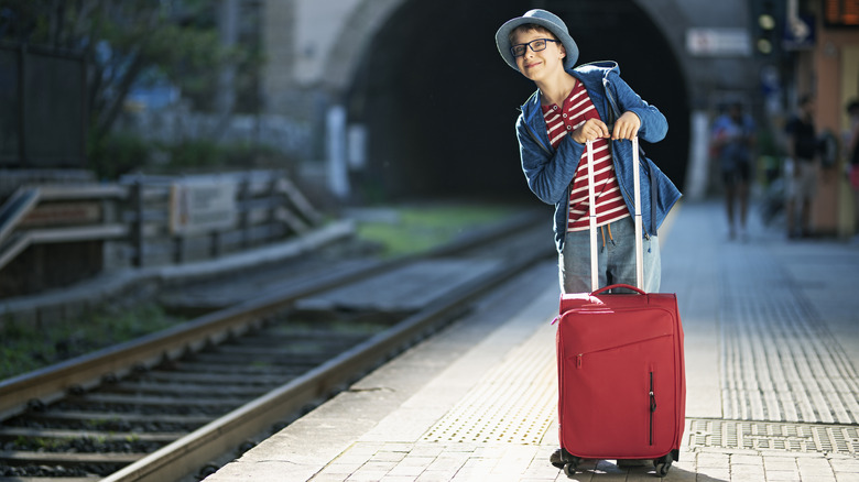 Boy with suitcase on train platform