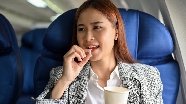 woman taking pill on plane