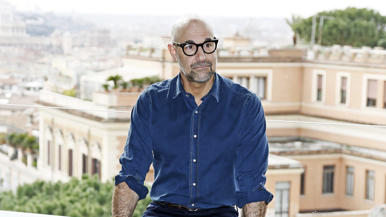 Stanley Tucci in front of buildings