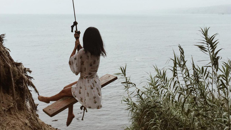 girl in white dress swinging over ocean